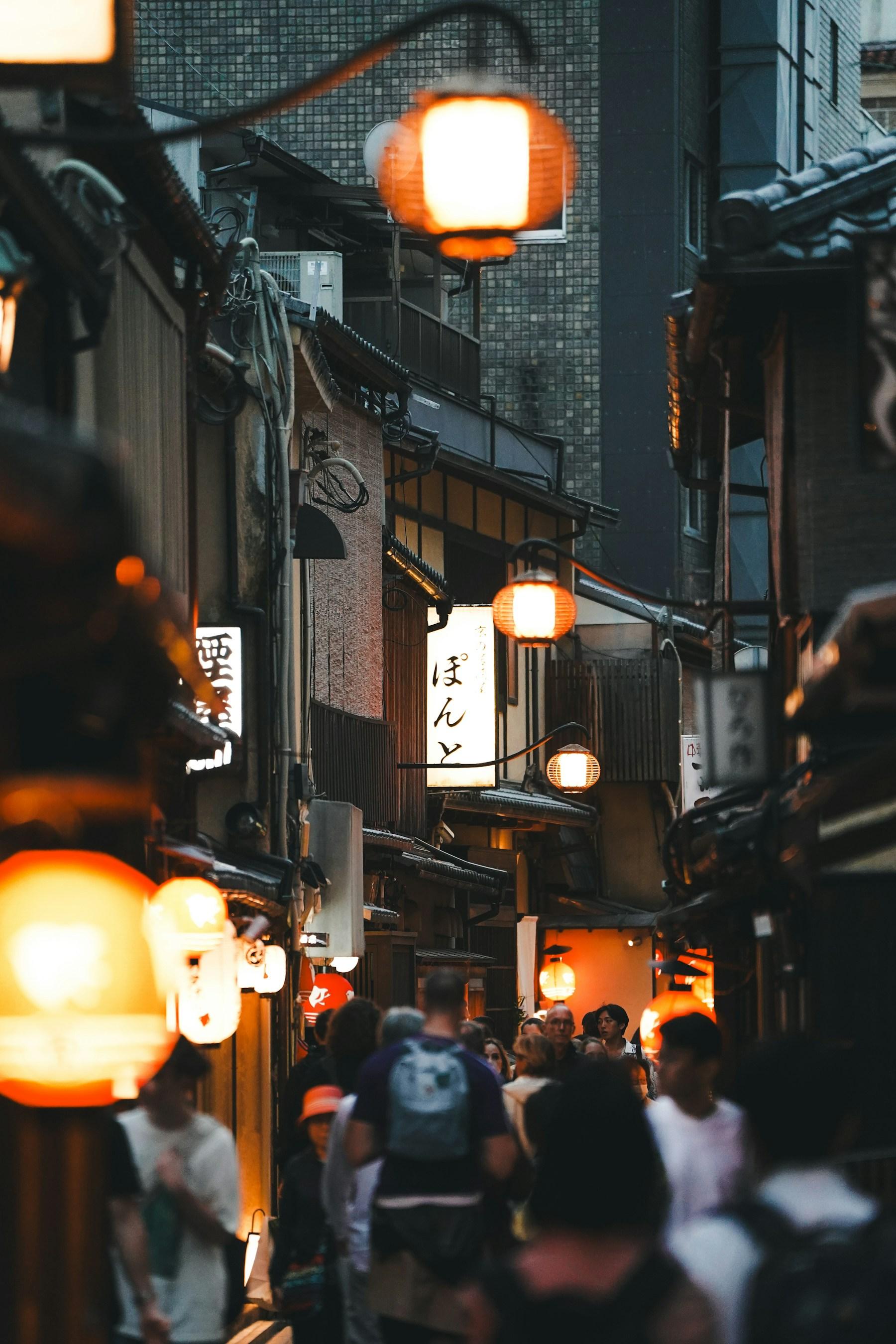 Letreiros em japonês e lanternas sobre uma rua movimentada de Kyoto